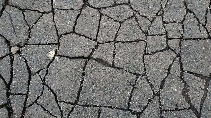 Alligator cracking across an asphalt surface, interconnected blocks with the cracks running full depth